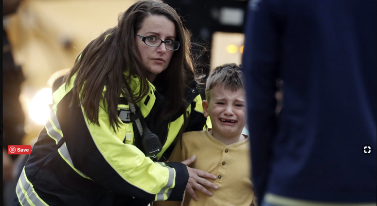 Officials guide students off a bus and into a recreation center where they were reunited with their parents after a shooting at a suburban Denver middle school Tuesday, May 7, 2019, in Highlands Ranch, Colo.