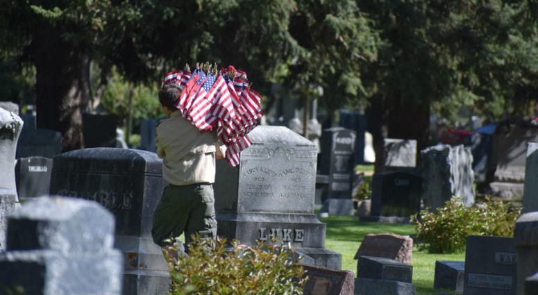A Boy Scout caries flags through Grandview Cemetery in Fort Collins, Colorado. Memorial Day weekend across America.