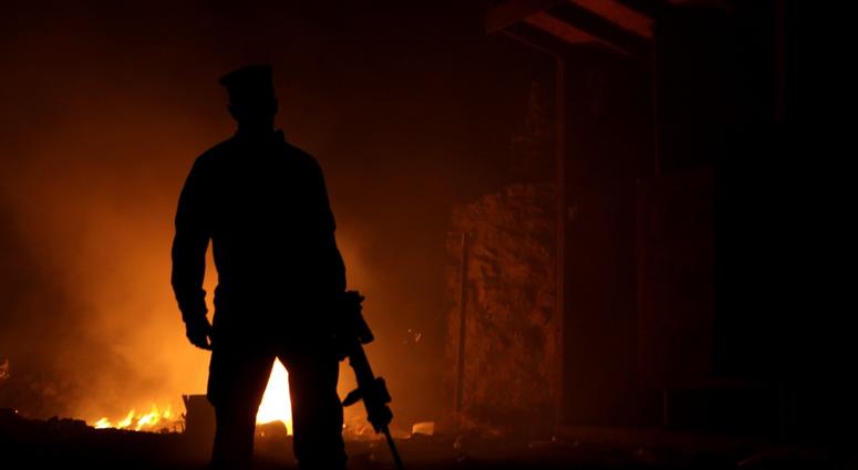 A Marine walks away after disposing of trash at the burn pit in Forward Operating Base (FOB) Zeebrudge, Helmand province, Afghanistan, March 6, 2013.