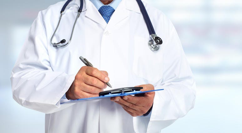 Doctor in white coat holding clipboard