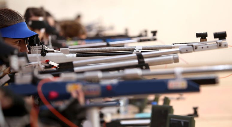 Young woman aiming a pneumatic air rifle on sports competition