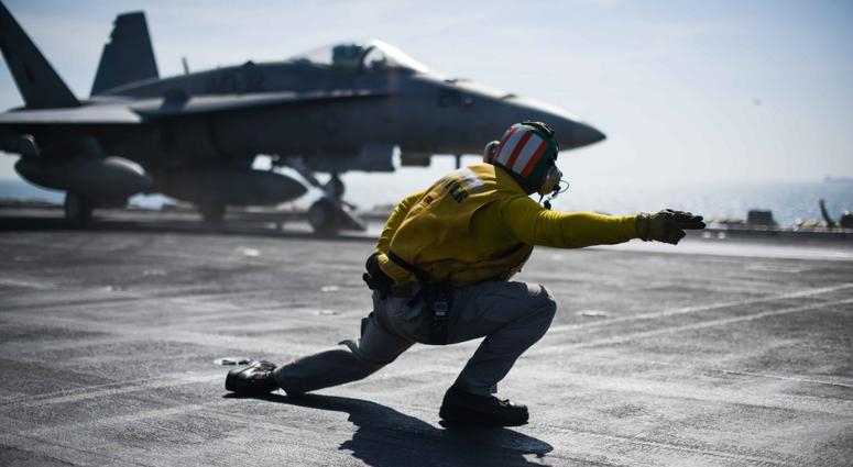 Lt. Donnell Exum signals an aircraft for launch on the flight deck of the aircraft carrier USS Theodore Roosevelt (CVN 71). Under Trump's new budget for the Pentagon, the Navy would increase sailors and add 10 new warships. Go