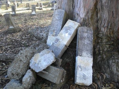Three headstones removed by the Russian government in 2010 rest near a tree.