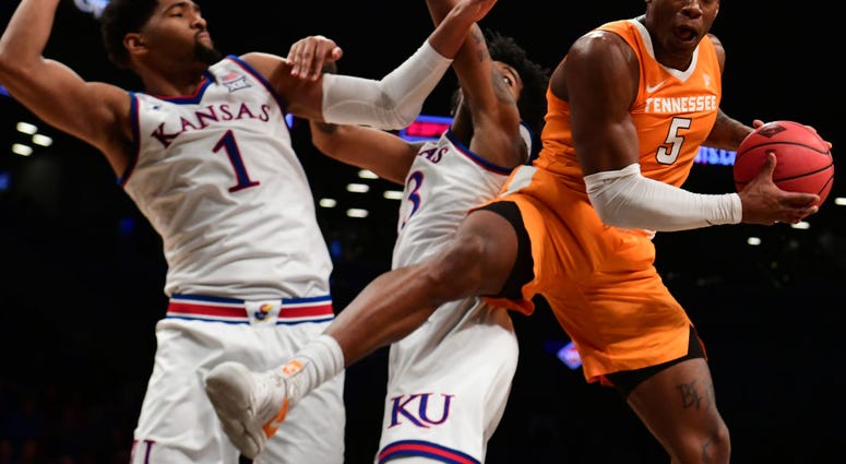 Photo of a Tennessee player being guraded by two Kansas players.