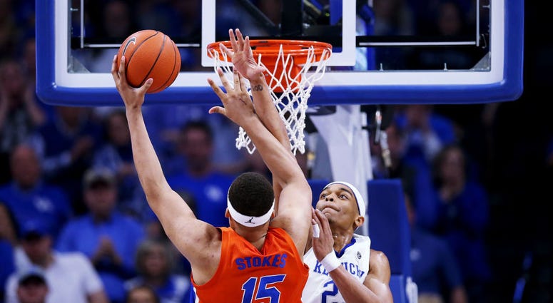 Photo of a Kentucky player contesting a possible dunk at the rim by a Florida player.