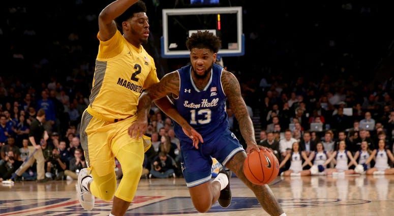 Photo of a Seton Hall player trying to dribble past a Marquette defender.