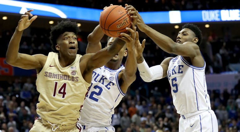 Photo of two Duke players and a Florida State player jumping for a rebound.