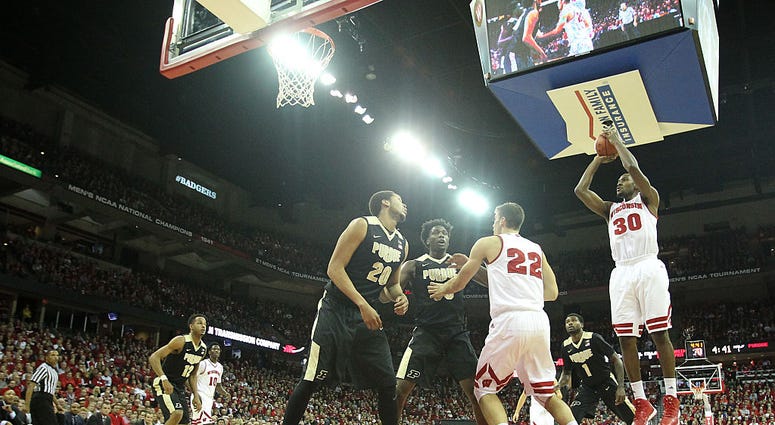 Photo of a Wisconsin player taking shot by two Purdue defenders.