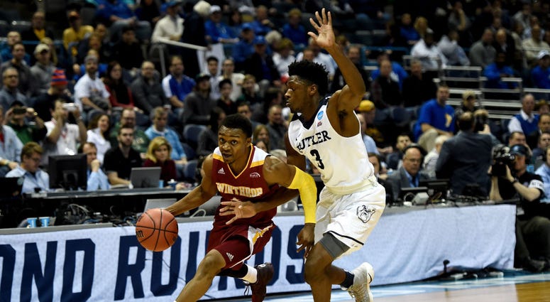Photo of a Winthrop player trying to dribble past a Butler player.