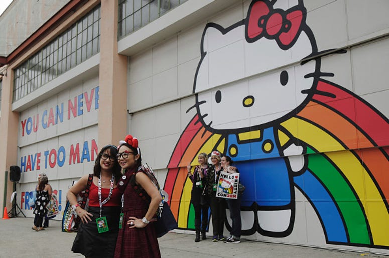 Tina Chinakarn, left, and Julie To, right, take a picture in front of a Hello Kitty mural outside of Hello Kitty Con October 31, 2014 at The Geffen Contemporary at MOCA in Los Angeles, California. Some 25,000 fans are expected to attend Hello Kitty Con be