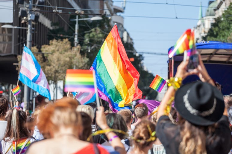 Picture of a crowd of people holding and raising rainbow flags, symbol of the homosexual struggle, during a gay demonstration. The rainbow flag, commonly known as the gay pride flag or LGBT pride flag, is a symbol of lesbian, gay, bisexual and transgender