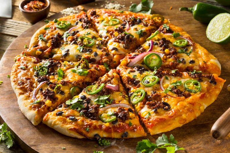 A whole pizza with sausage, olives and peppers