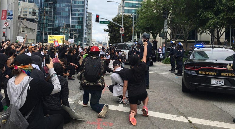 Protesters kneel in front of police at a San Francisco rally.