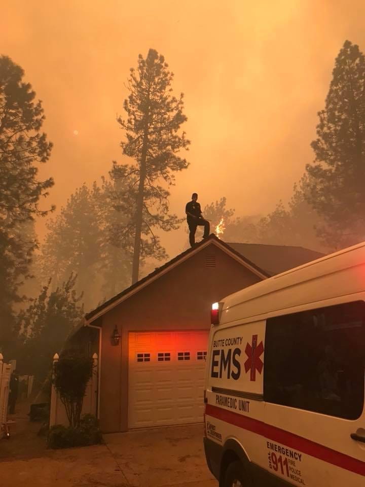 Mike Castro, of the Butte County EMS, stands on top of a home and defends it from the Camp Fire.