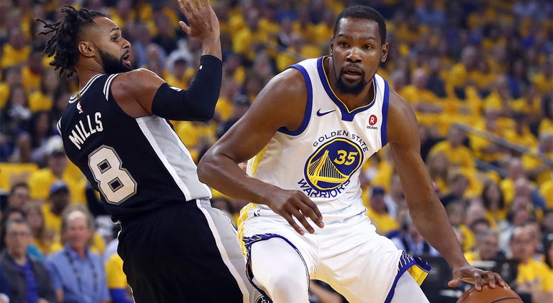 AP18104722655473 Golden State Warriors' Kevin Durant, right, drives the ball around San Antonio Spurs' Patty Mills (8) during the first half in Game 1 of a first-round NBA basketball playoff series Saturday, April 14, 2018, in Oakland, Calif. (AP Photo/Ben Margot)