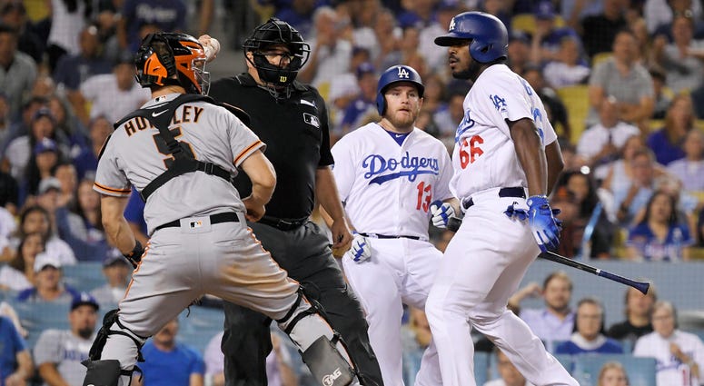 AP18227180537247 San Francisco Giants catcher Nick Hundley, left, reacts to being shoved by Los Angeles Dodgers' Yasiel Puig, right, as they argue while home plate umpire Eric Cooper, second from left, gets between them and Max Muncy runs in during the seventh inning of a