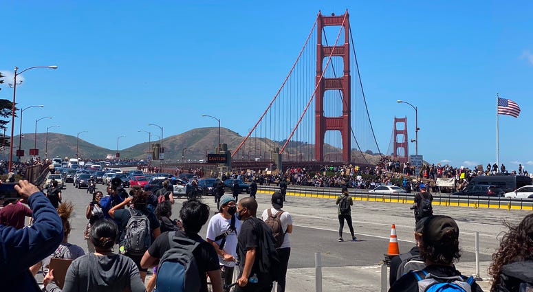 Black Lives Matter protesters march across and on to the roadway at the Golden Gate Bridge.