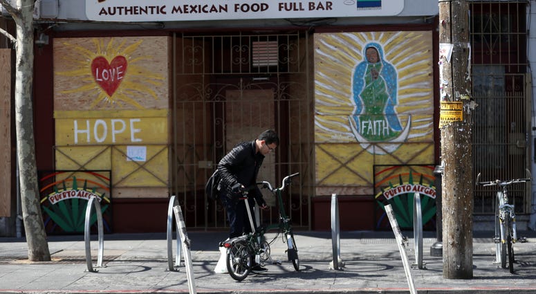 cyclist parks his bicycle in front of a business that has the windows covered with plywood on Valencia Street on March 20, 2020 in San Francisco cyclist parks his bicycle in front of a business that has the windows covered with plywood on Valencia Street on March 20, 2020 in San Francisco