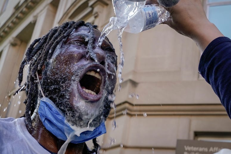 A demonstrator is doused with water and milk after being hit with pepper spray from law enforcement during a protest on June 1, 2020 in downtown Washington, DC. A demonstrator is doused with water and milk after being hit with pepper spray from law enforcement during a protest on June 1, 2020 in downtown Washington, DC.