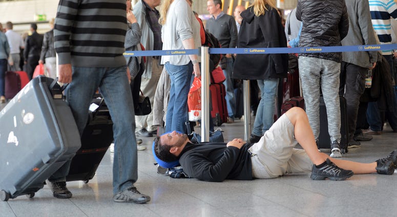 : A passenger takes a nap as other passengers wait in line for Lufthansa flights on October 20, 2014 in Frankfurt am Main, Germany : A passenger takes a nap as other passengers wait in line for Lufthansa flights on October 20, 2014 in Frankfurt am Main, Germany