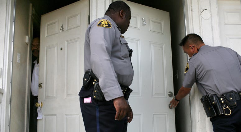 A neighbor peers out of his door as Alameda County Sheriff deputies Ken Cammack (C) and Ken Kong (R) enter an apartment to evict tenants who have defaulted on rent payments June 4, 2009. A neighbor peers out of his door as Alameda County Sheriff deputies Ken Cammack (C) and Ken Kong (R) enter an apartment to evict tenants who have defaulted on rent payments June 4, 2009.