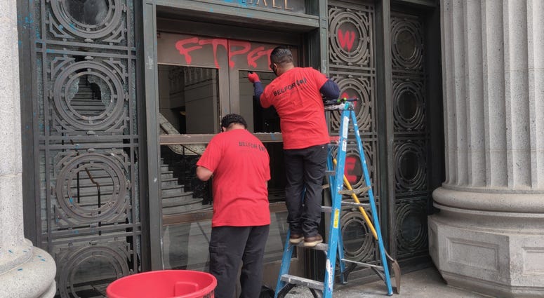 Workers repair smashed windows at Oakland City Hall.