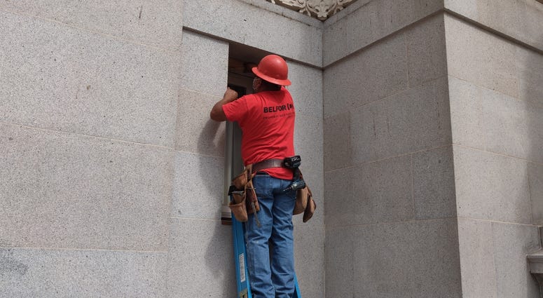 Workers repair smashed windows at Oakland City Hall.