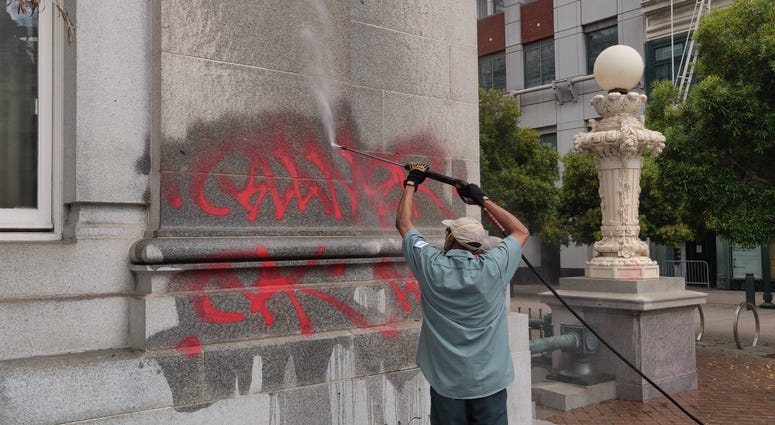 Workers clean graffiti from Oakland City Hall.