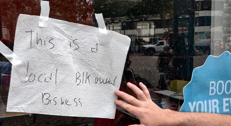 A sign labels a business as "black-owned" and calls for peace in Oakland
