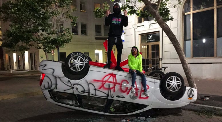A flipped over car in downtown Oakland.