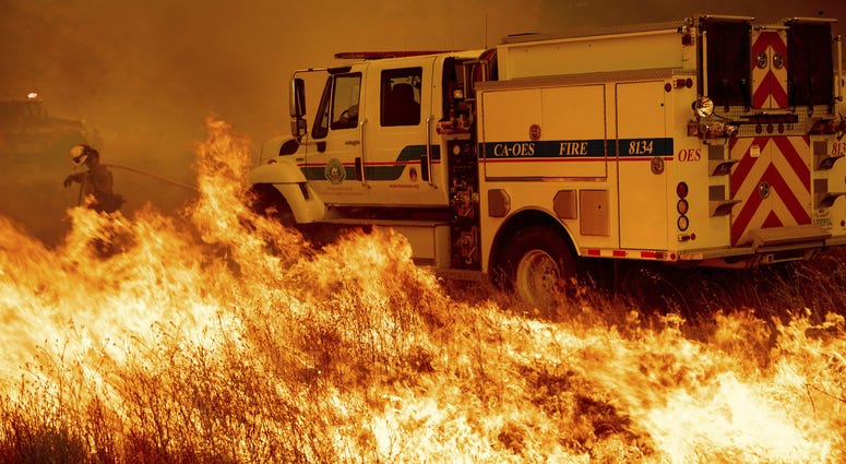 A firefighter scrambles to stop the Pawnee fire as it spots across Highway 20 near Clearlake Oaks, Calif., on Sunday, July 1, 2018.