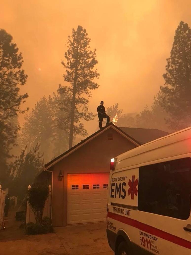 Mike Castro, of the Butte County EMS, stands on top of a home and defends it from the Camp Fire.