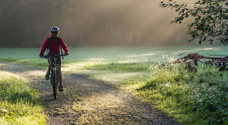 A woman rides an e-bike along a nature trail A woman rides an e-bike along a nature trail