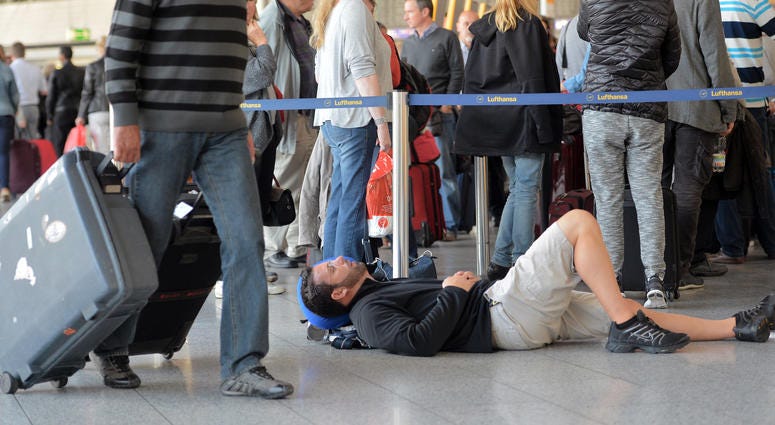 : A passenger takes a nap as other passengers wait in line for Lufthansa flights on October 20, 2014 in Frankfurt am Main, Germany : A passenger takes a nap as other passengers wait in line for Lufthansa flights on October 20, 2014 in Frankfurt am Main, Germany