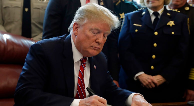 In this March 15, 2019, file photo, President Donald Trump signs the first veto of his presidency in the Oval Office of the White House in Washington. DO NOT USE