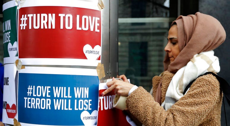 A demonstrator hangs banners from multi-faith group 'Turn to Love' during a vigil at New Zealand House in London, Friday, March 15, 2019. DO NOT USE