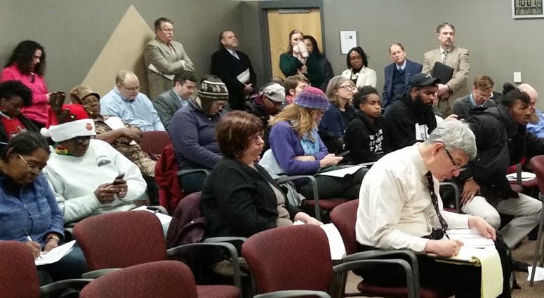 people sit in rows of chairs attending a board meeting