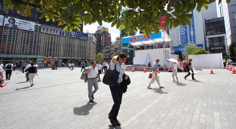 People make their way in the scorching heat at a business district in Tokyo, Monday, July 23, 2018. DO NOT USE