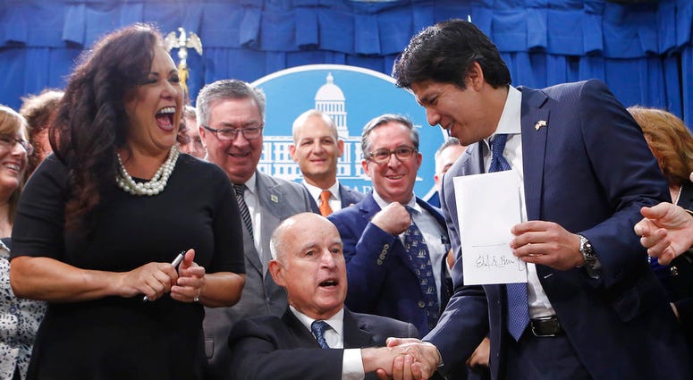 State Sen. Kevin de Leon, D-Los Angeles, right, shakes hands with Gov. Jerry Brown after Brown signed his environmental measure SB100, Monday, DO NOT USE