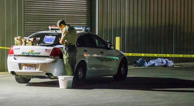 A Kern County sheriff's deputy stands near an area where a shooting victim lies, Wednesday, Sept. 12, 2018, in Bakersfield, Calif. DO NOT USE