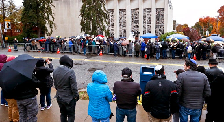 People line both sides of the street as they gather outside the Tree of Life Synagogue for a service on Saturday, Nov. 3, 2018, in Pittsburgh. About 100 people gathered in a cold drizzle for what was called a "healing service" outside the synagogue DO NOT USE