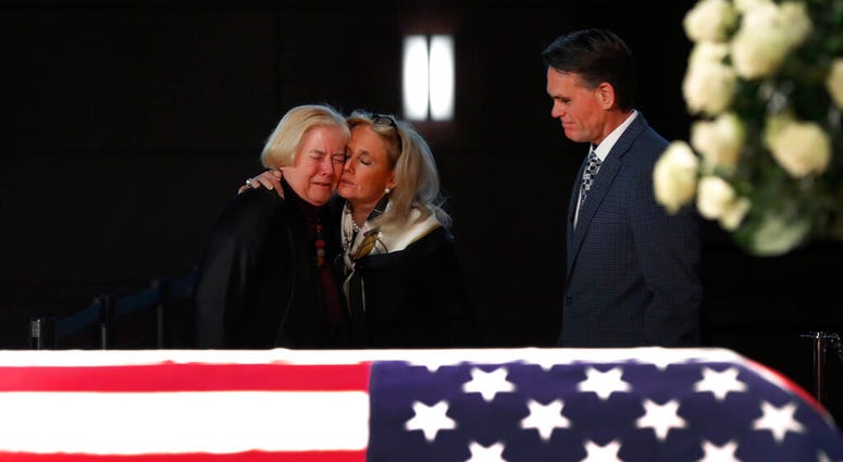 Rep. Debbie Dingell, D-Mich., center, consoles former Rep. Candice Miller, R-Mich., as Macomb County executive Mark Hackel, right, looks on at the casket of her husband and former Rep. John Dingell, lying in repose in Dearborn, Mich., Monday, Feb. 11, 201 Rep. Debbie Dingell, D-Mich., center, consoles former Rep. Candice Miller, R-Mich., as Macomb County executive Mark Hackel, right, looks on at the casket of her husband and former Rep. John Dingell, lying in repose in Dearborn, Mich., Monday, Feb. 11, 201