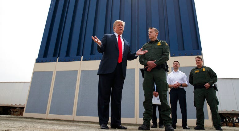 President Donald Trump talks with reporters as he reviews border wall prototypes in San Diego. AP DO NOT USE