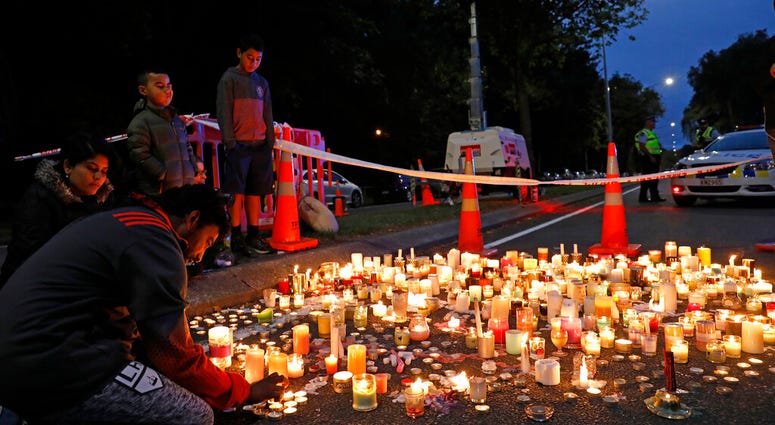 A mourner lights a candle during a vigil to commemorate victims of Friday's shooting, outside the Al Noor mosque in Christchurch, New Zealand AP DO NOT USE