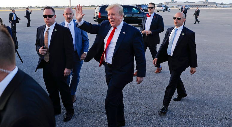 In this April 18, 2019, photo, President Donald Trump, center, surrounded by members of the Secret Service, walks across the tarmac to begin to greet supporters during his arrival at Palm Beach International Airport, Thursday, April 18, 2019, in West Palm AP DO NOT USE