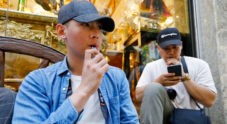 In this Monday, June 17, 2019, photo, Joshua Ni, 24, and Fritz Ramirez, 23, vape from electronic cigarettes in San Francisco. AP DO NOT USE