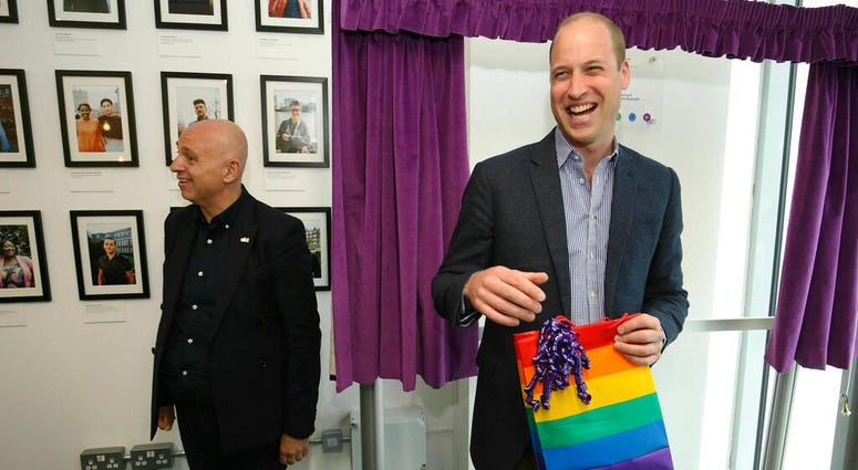 Britain's Prince William, the Duke of Cambridge, reacts to receiving a gift bag from trust chief executive officer Tim Sigsworth, during a visit to the Albert Kennedy Trust to learn about the issue of LGBTQ youth homelessness and the unique approach that
