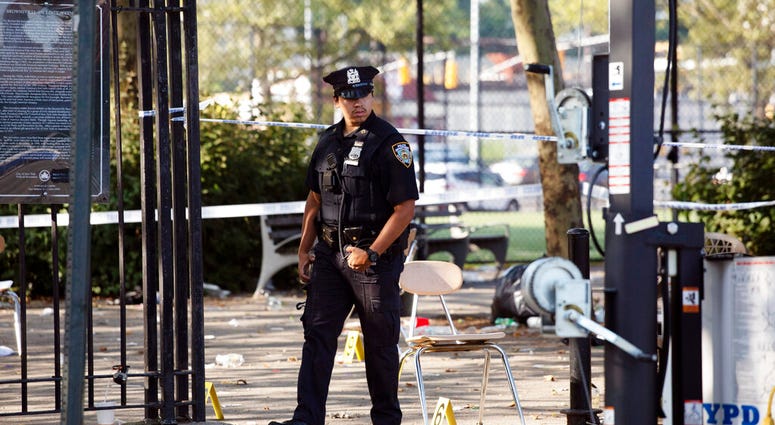 A police officer walks by yellow evidence markers at a playground in the Brownsville neighborhood in the Brooklyn borough of New York, Sunday, July 28, 2019. Police said, one man was killed and at least 11 others were injured in a shooting late Saturday n A police officer walks by yellow evidence markers at a playground in the Brownsville neighborhood in the Brooklyn borough of New York, Sunday, July 28, 2019. Police said, one man was killed and at least 11 others were injured in a shooting late Saturday n