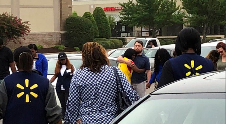 In this image provided by WREG-TV, Walmart employees join in a prayer circle outside the store Tuesday, July 30, 2019, in Southaven, Miss. DeSoto County Sheriff Bill Rasco says one person is dead and a suspect was shot.