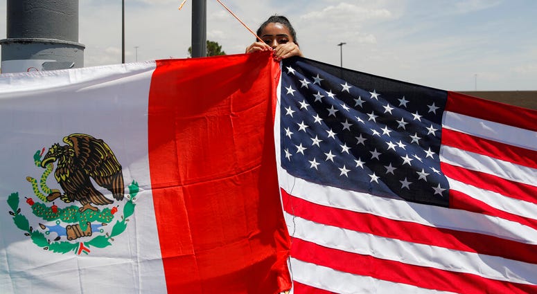 Maylin Reyes hangs a Mexican flag at a makeshift memorial near the scene of a mass shooting at a shopping complex Monday, Aug. 5, 2019, in El Paso, Texas. AP DO NOT USE